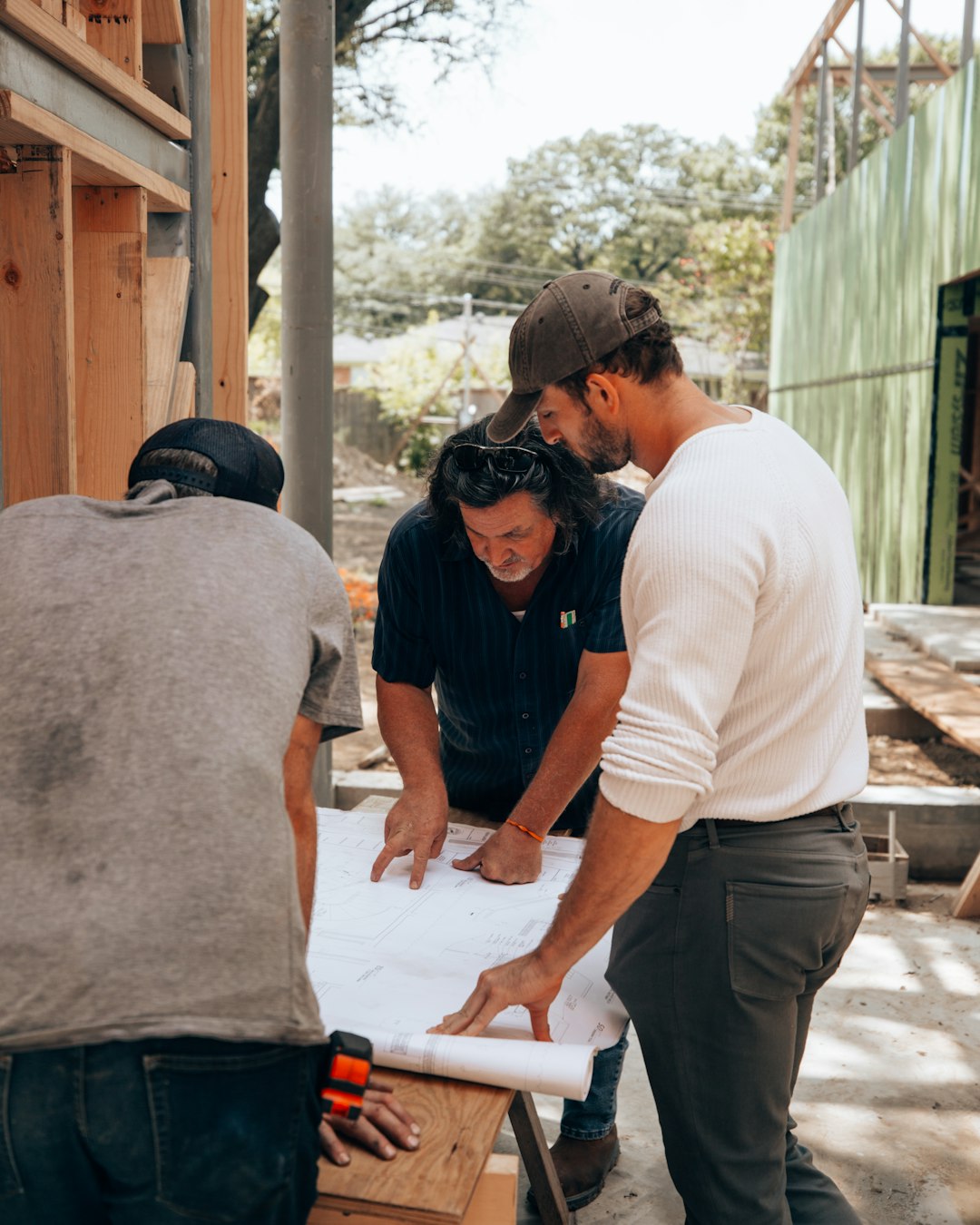 Grupo de técnicos con casco revisando planos sobre una mesa de trabajo en obra