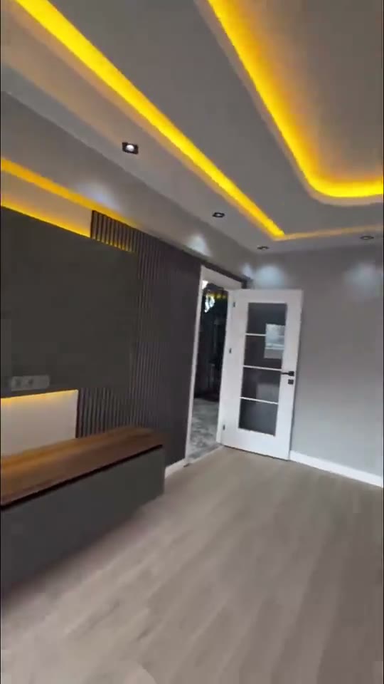 Sala remodelada por nuestro equipo, con mueble de TV, paneles ranurados e iluminación LED indirecta